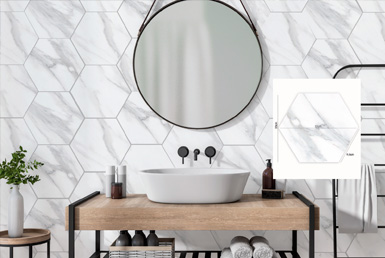 CERAMICA-HEXAGONAL-CALACATA--20X23-CM Cerámica hexagonal en baño de restaurante blanco con betas rectificado con espejo redondo y lavamanos blanco, mesa de madera.