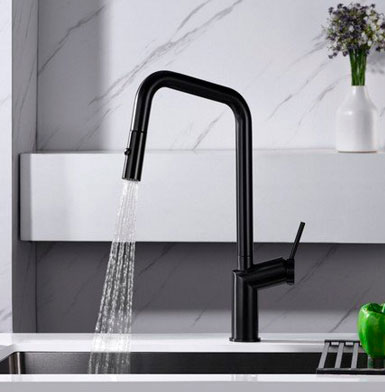 griferia-BONN-NEGRO-MATE Agua con grifo de cocina negro mate y lavaplatos negro con meson blanco , y pared con porcelanato blanco con vetas negras y florero con flores