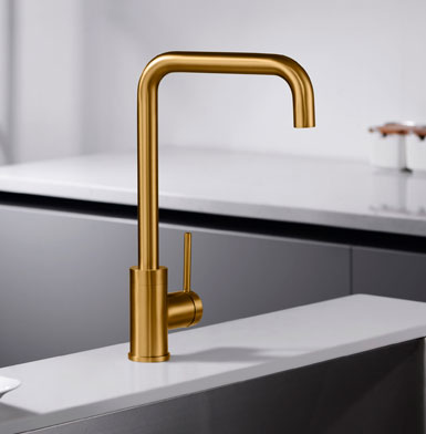 grifewria-LOIRA-ORO-CEPILLADO Grifo para cocina dorada elegante y moderno con meson blanco puro y pared blanca